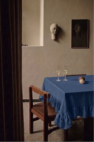 Navy ruffled linen cotton blend tablecloth on a dining table with champagne flutes, seen through a doorway. 9 sizes, handmade in Denizli, OEKO-TEX. VivaMaison.