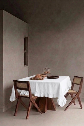White ruffled linen cotton blend tablecloth on a dining table in a modern dining room with cane chairs. 9 sizes, handmade in Denizli, OEKO-TEX. VivaMaison.