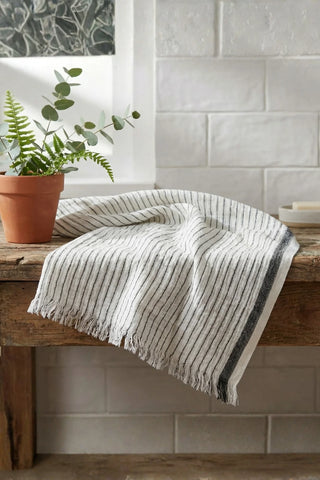 Muslin striped Turkish cotton beach towel peshtemal with black stripes on a rustic bathroom bench - VivaMaison