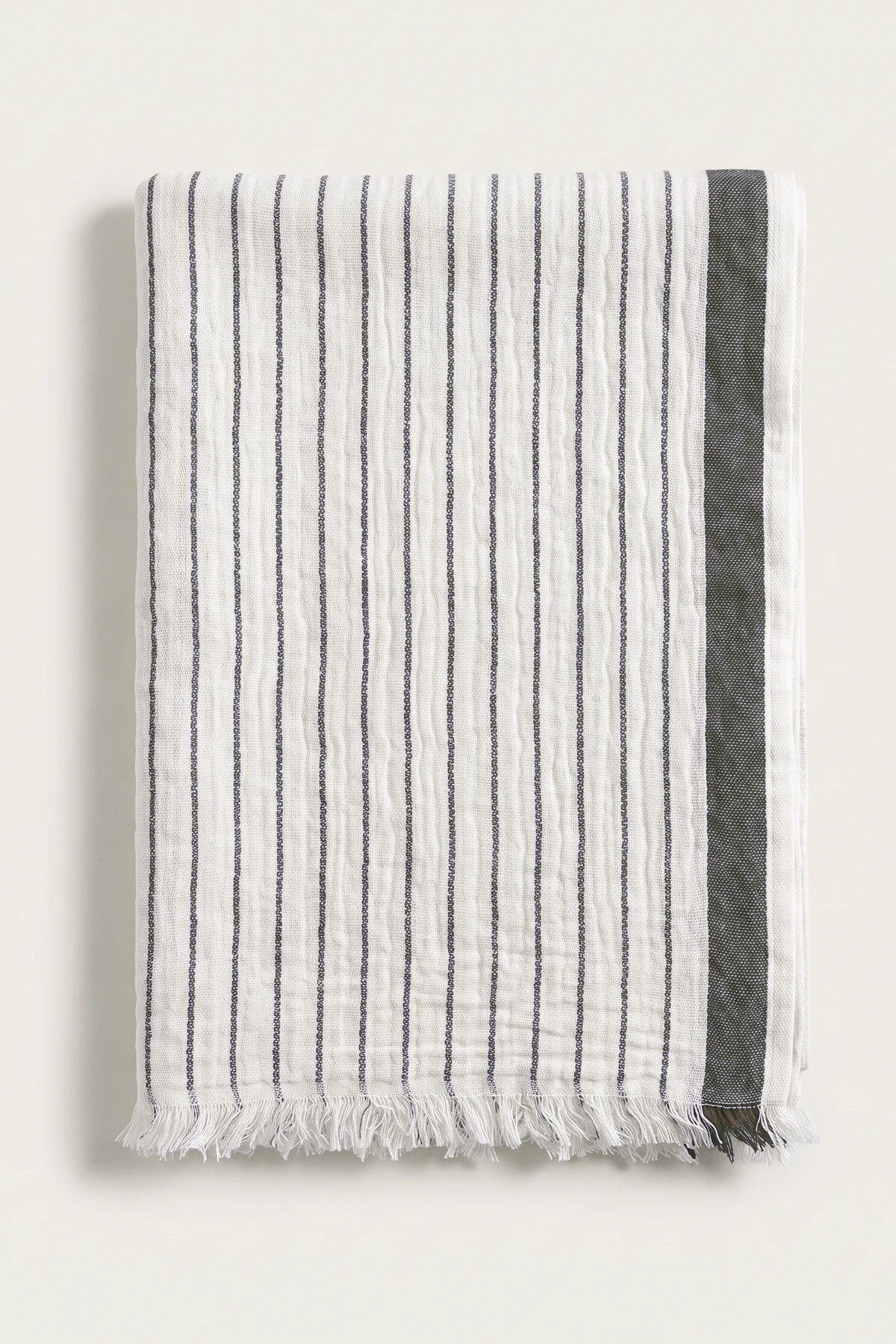 Muslin striped Turkish cotton beach towel peshtemal in black, folded front view with side band and short fringe