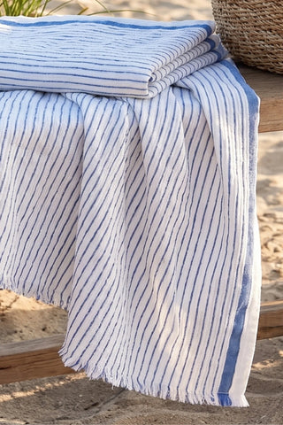 Close-up of muslin striped turkish cotton beach towel peshtemal with blue stripes on the beach - VivaMaison
