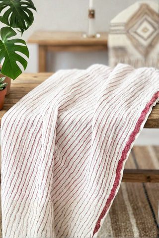 Muslin striped Turkish cotton beach towel peshtemal with red stripes draped over a wooden bench - VivaMaison