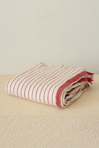 Muslin striped Turkish cotton beach towel peshtemal with red stripes folded on stone pedestal - VivaMaison