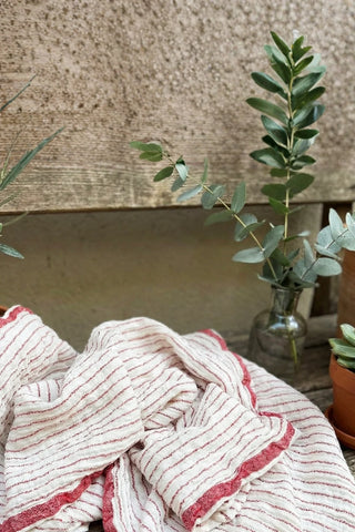 Muslin striped Turkish cotton beach towel peshtemal with red stripes outdoors in a garden setting - VivaMaison