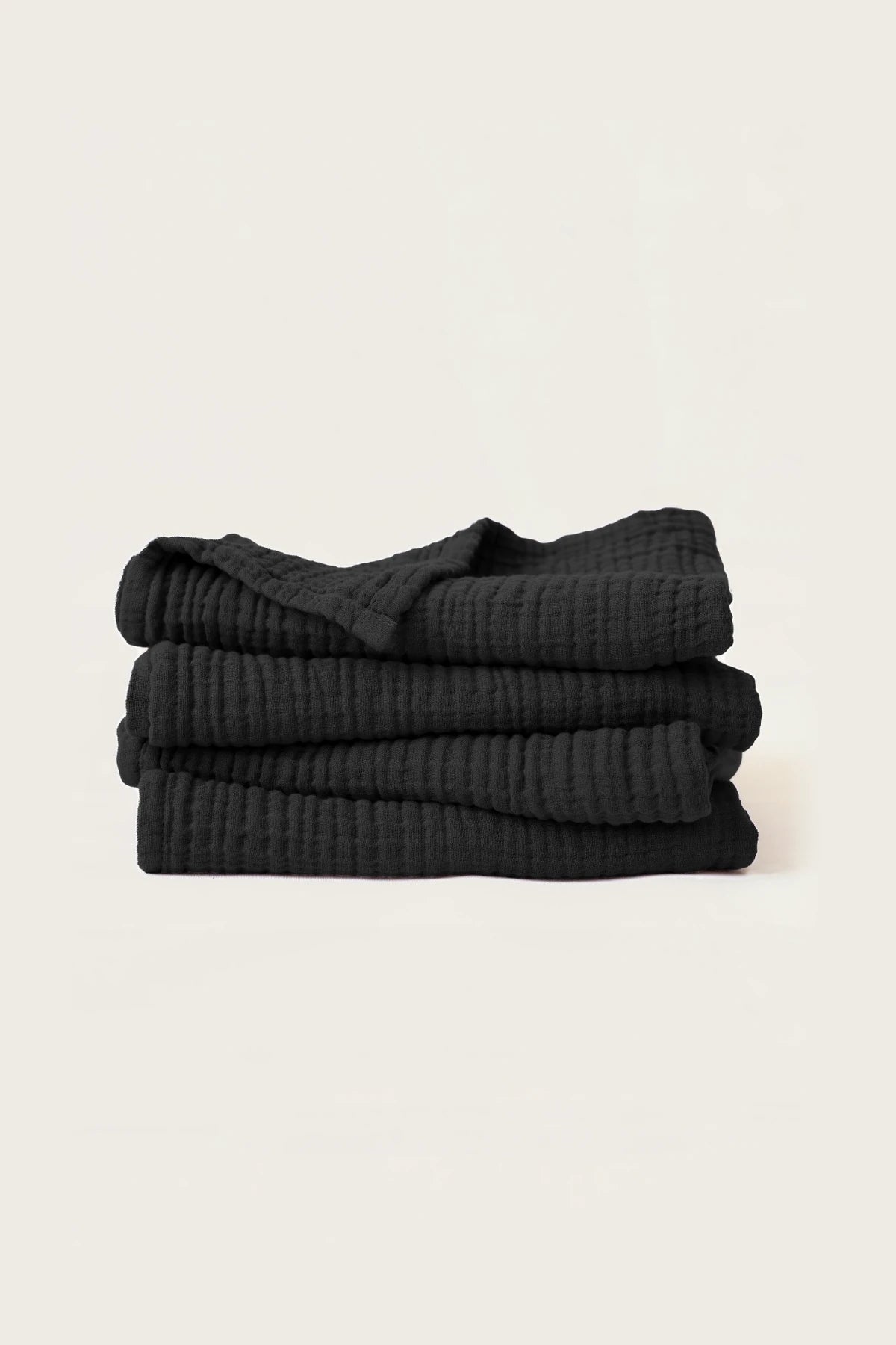 Stacked black muslin Turkish cotton towels with soft 4-layer gauze weave, handwoven in Denizli