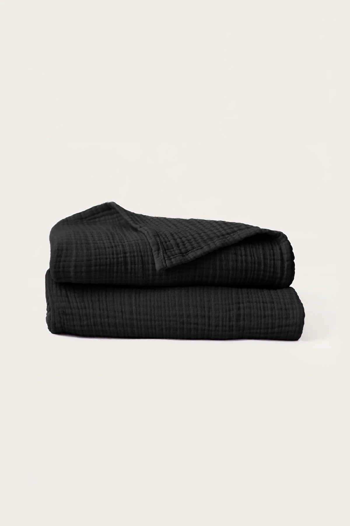 Folded black handwoven muslin towels showing the breathable 4-layer cotton texture by VivaMaison