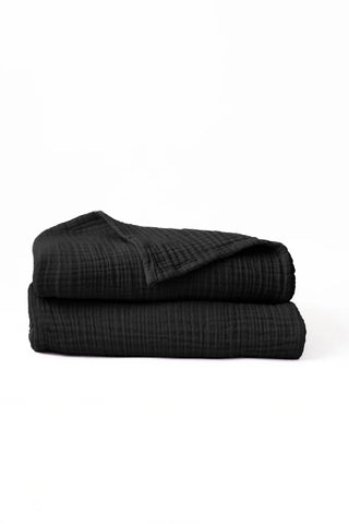 Folded black handwoven muslin towels showing the breathable 4-layer cotton texture by VivaMaison