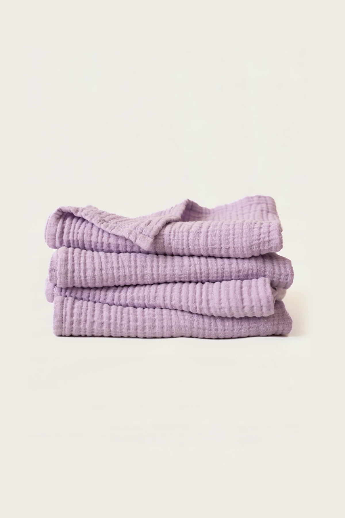 Neatly stacked lilac muslin Turkish towels highlighting the soft gauze layers, OEKO-TEX certified Denizli