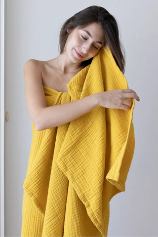 Mustard 4-layer muslin bath towel styled in a bathroom — Turkish cotton, OEKO-TEX certified Denizli