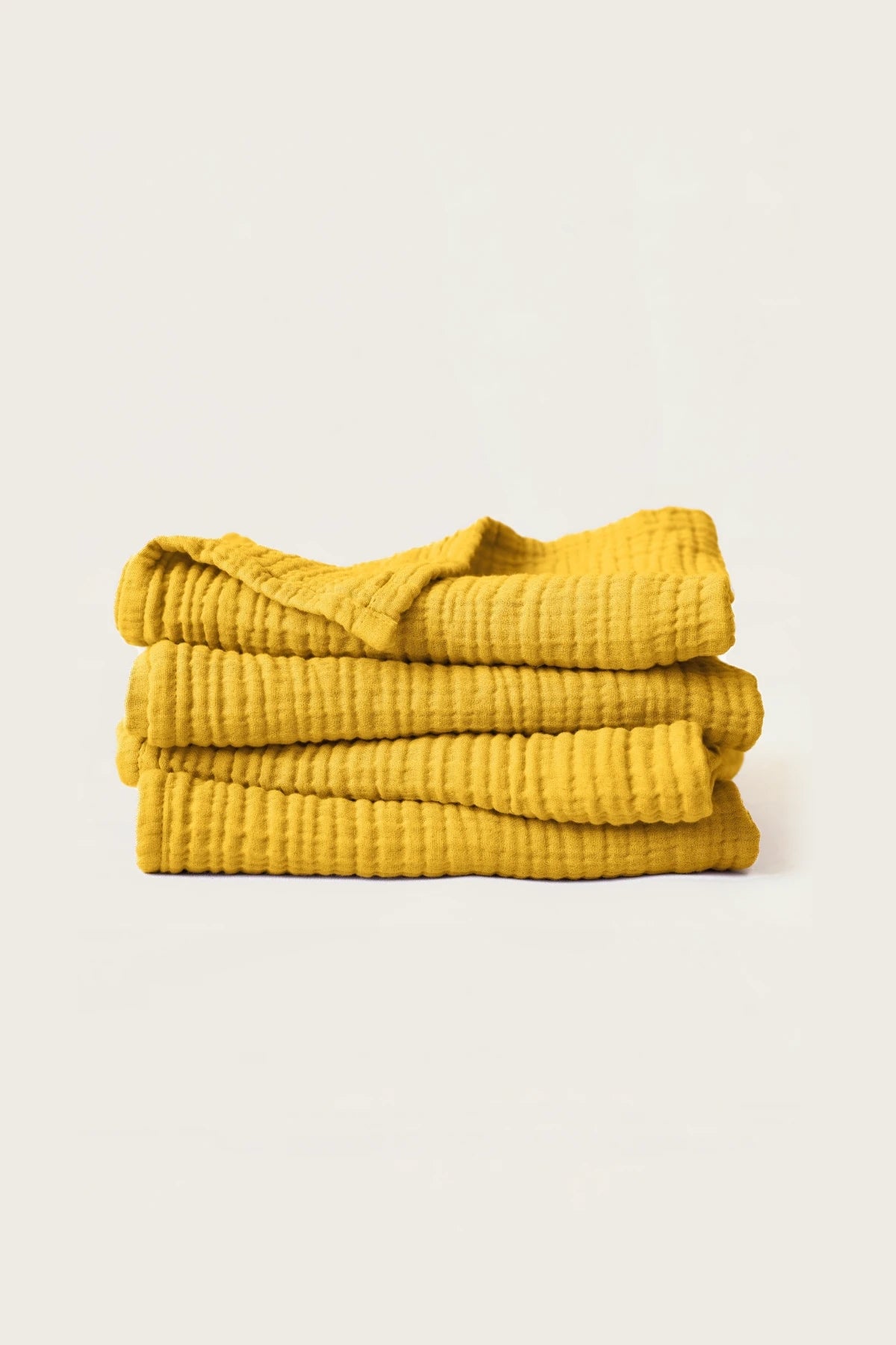 Stacked mustard muslin Turkish cotton towels with soft 4-layer gauze weave, handwoven in Denizli