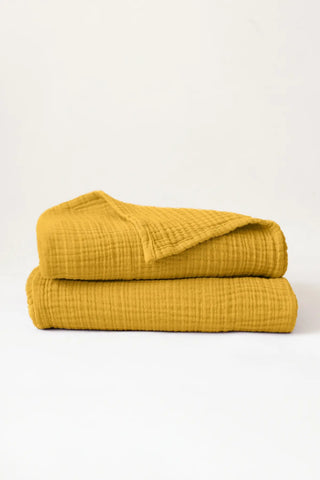 Folded mustard handwoven muslin towels showing the breathable 4-layer cotton texture by VivaMaison