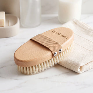 Natural bristle dry body brush on a bathroom shelf with towels and a candle - VivaMaison