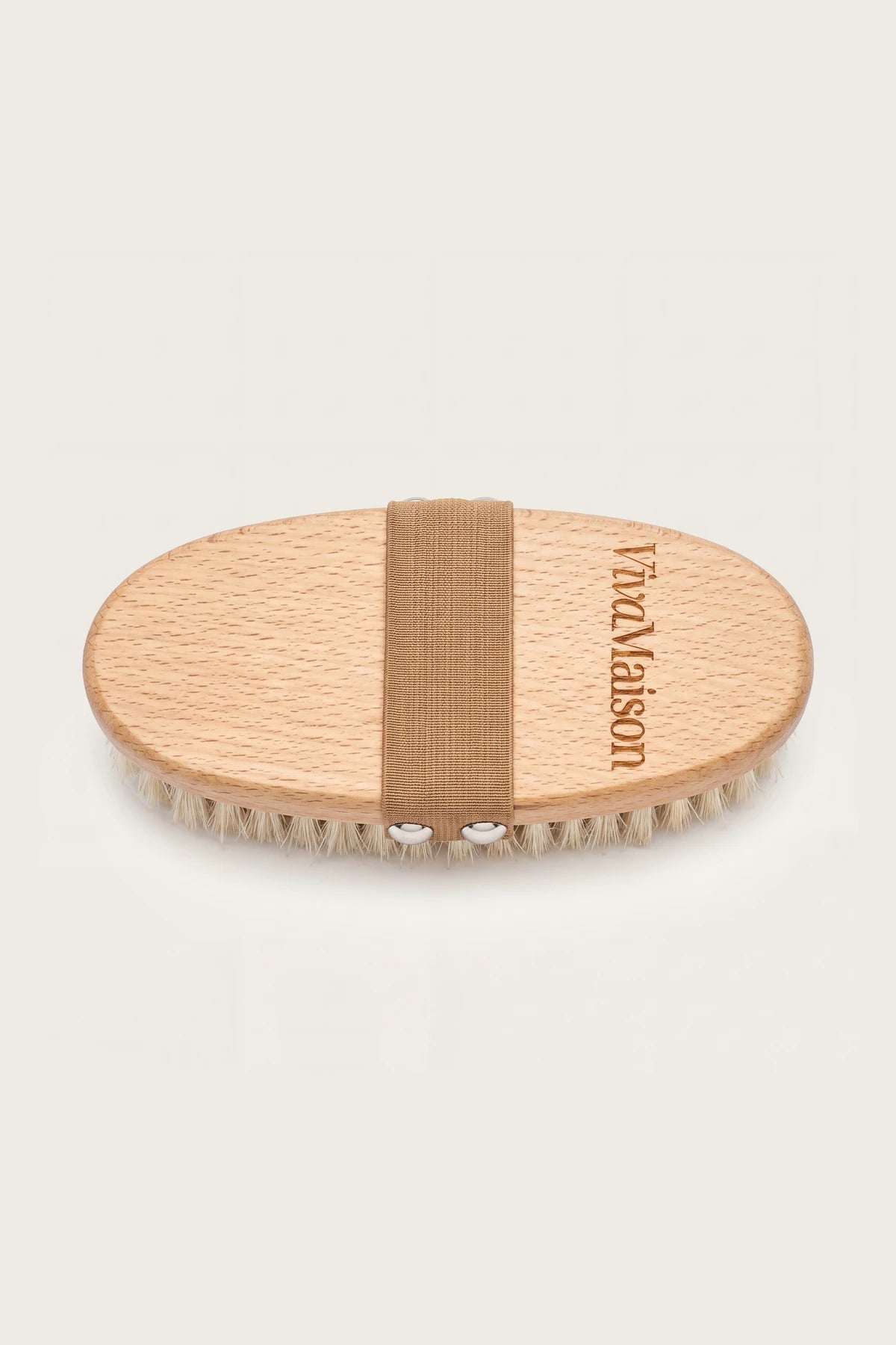 Natural bristle dry body brush with oval beech wood body and elastic hand strap on white background - VivaMaison