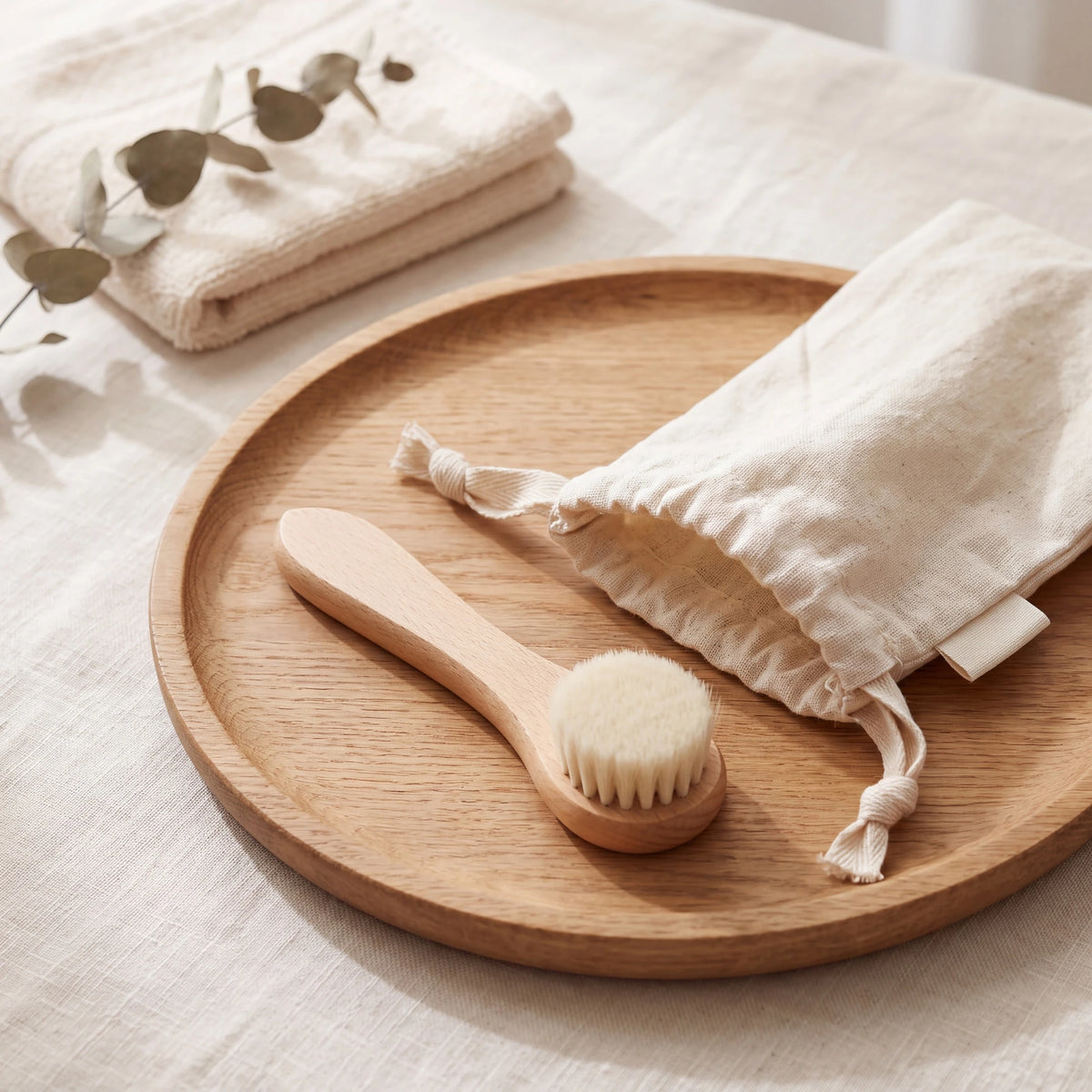 Natural bristle dry face brush with its cotton drawstring pouch on a wooden tray - VivaMaison