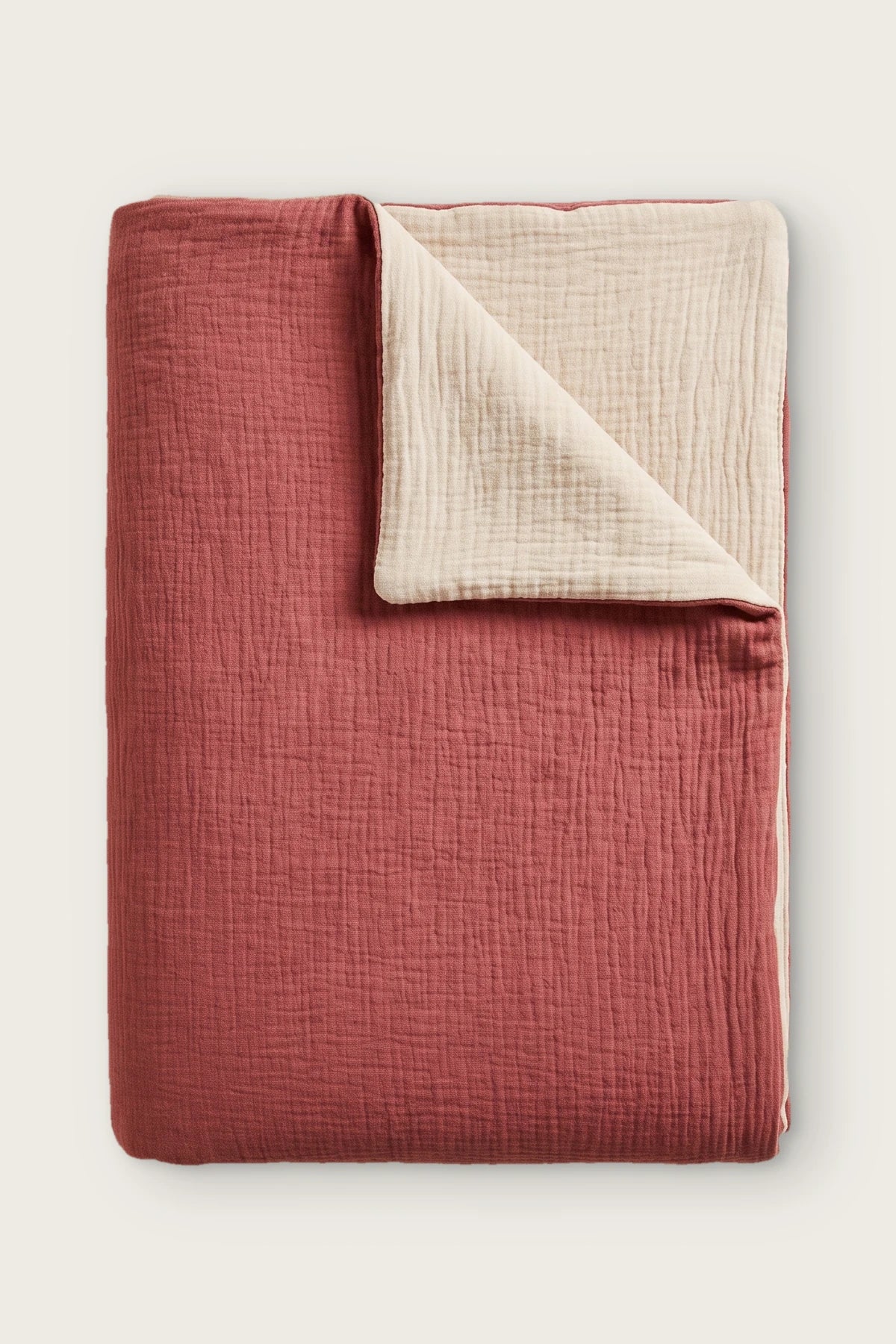 Reversible two-tone muslin duvet cover in terracotta / ecru, folded view showing both sides