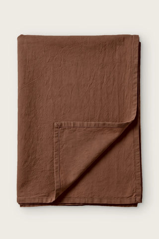 Brown handwoven stonewashed Turkish cotton tablecloth, folded with corner turned back. Vintage-soft Denizli, OEKO-TEX. VivaMaison