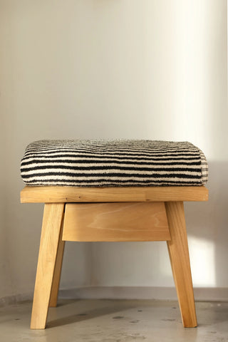 Black striped Turkish cotton bath sheet folded on a wooden stool - VivaMaison