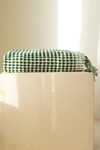 Green White Turkish cotton pom pom towel folded on a plinth - VivaMaison