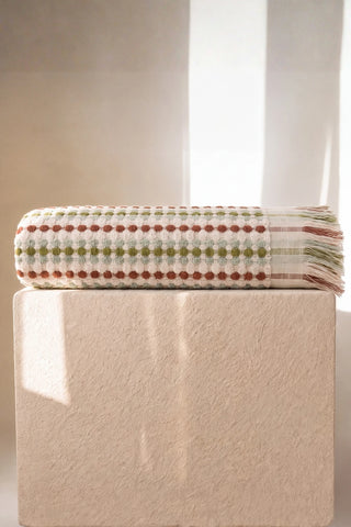 Sage Brown Turkish cotton pom pom towel folded on a plinth - VivaMaison
