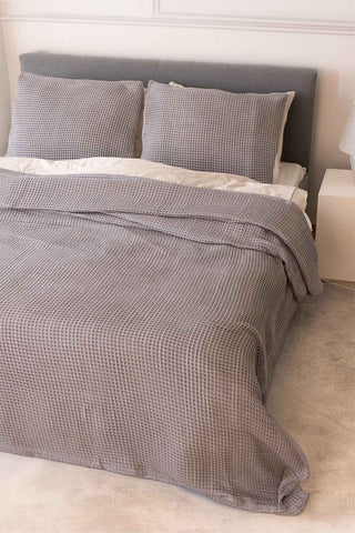 Natural waffle bedspread draped on bed showing honeycomb weave texture by Vivamaison