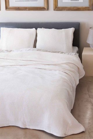 Natural waffle bedspread draped on bed showing honeycomb weave texture by Vivamaison